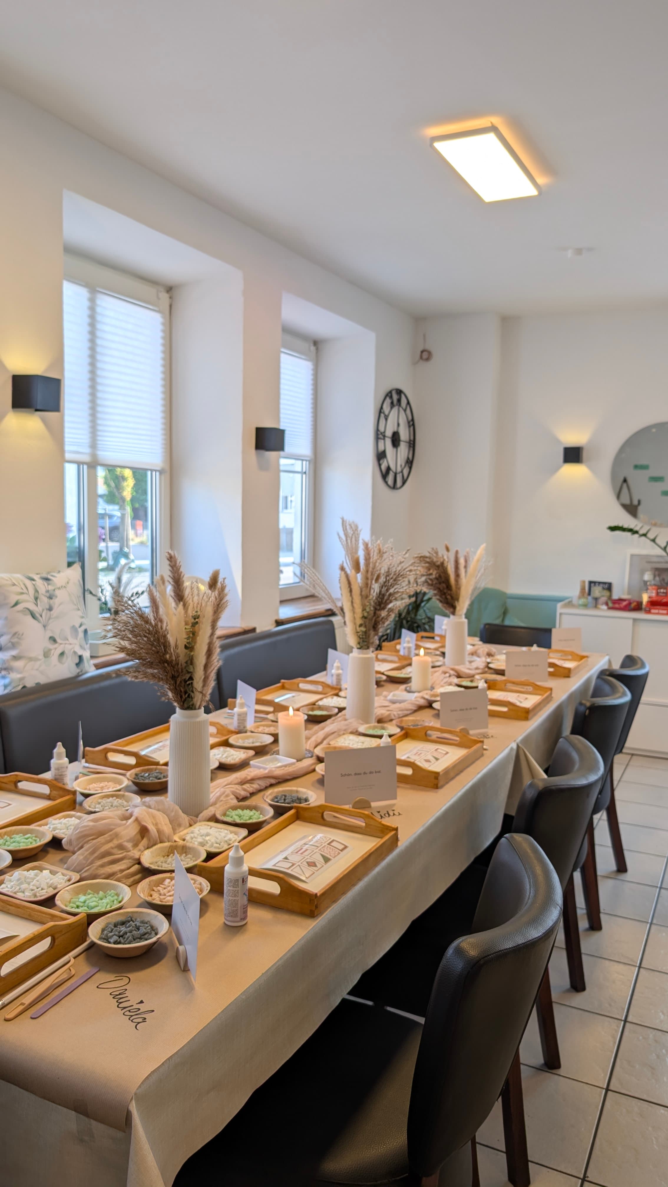 Festlich gedeckter Tisch mit Holztabletts, Trockenblumen und bunten Mosaiksteinen für einen kreativen Workshop.