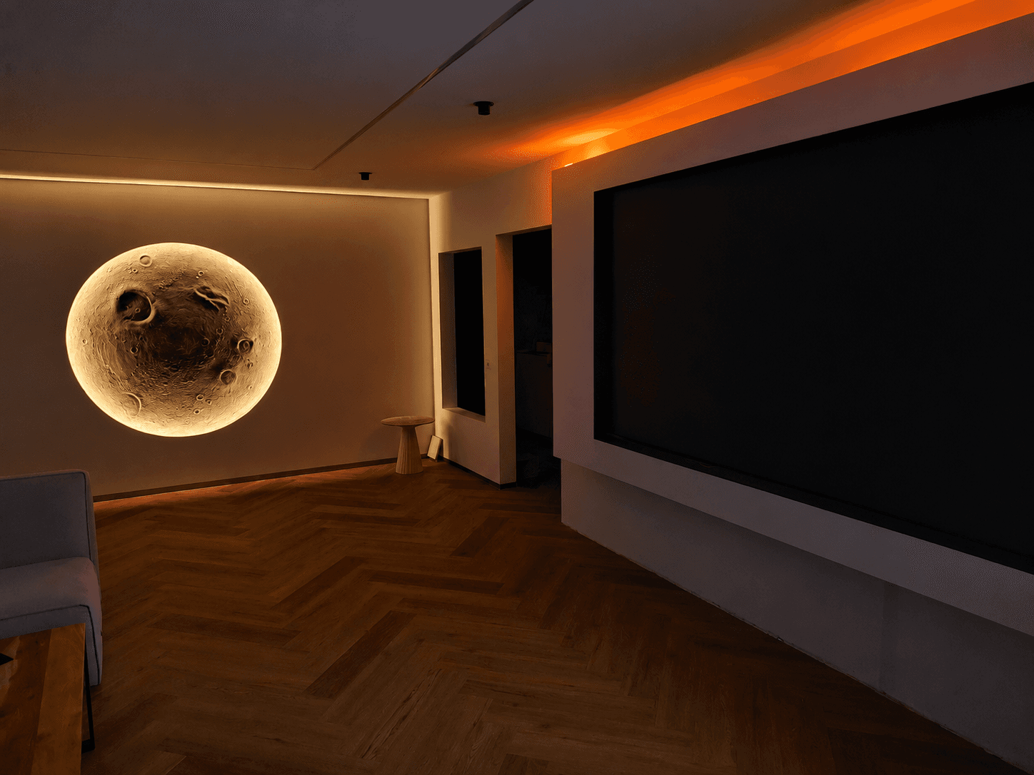 Modernes Wohnzimmer mit leuchtender Mondlampe, Fischgrätparkett und großer Leinwand unter einem warmen, orangefarbenen Lichtakzent.